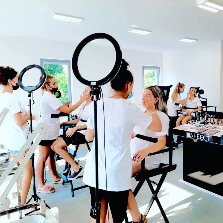 Hands-on makeup training in small groups during practical beauty workshops.