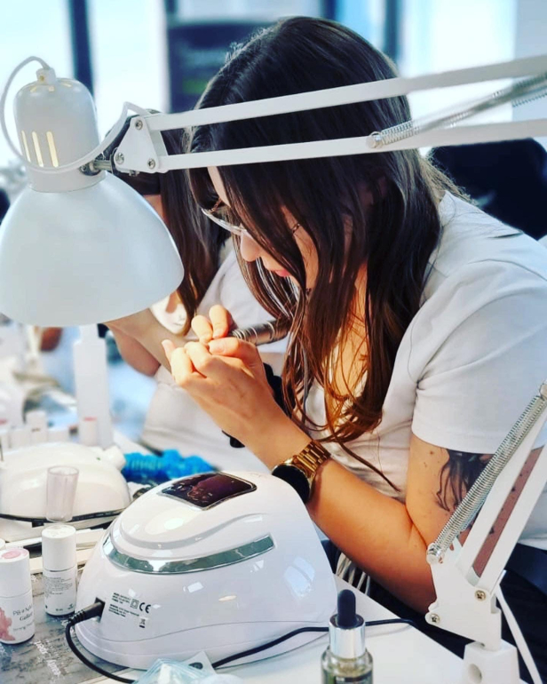Hands-on nail technician training covering nail extensions, hand treatments, and electric nail file techniques.
