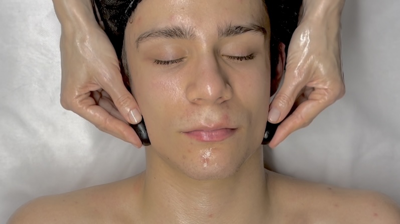 Facial stone massage – use of hot basalt stones and cold marble stones during the practical lesson in the one-year beauty school program.