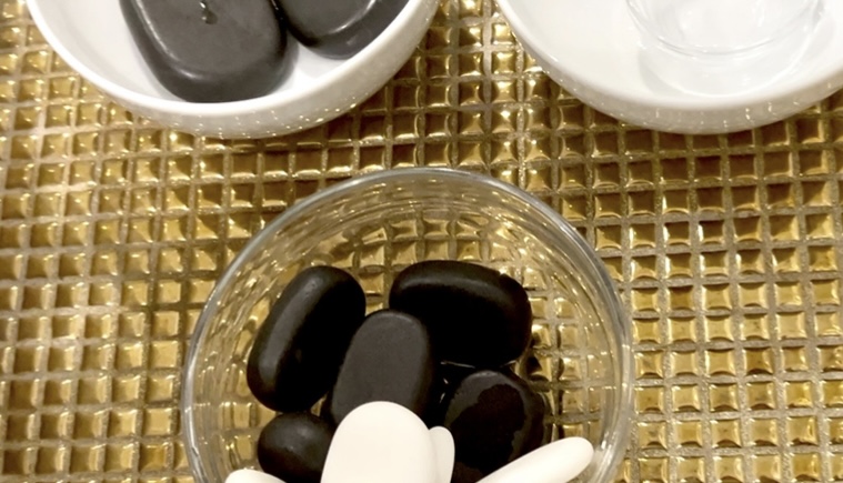 kamienie bazaltowe do masażu ułożone na stole zabiegowym