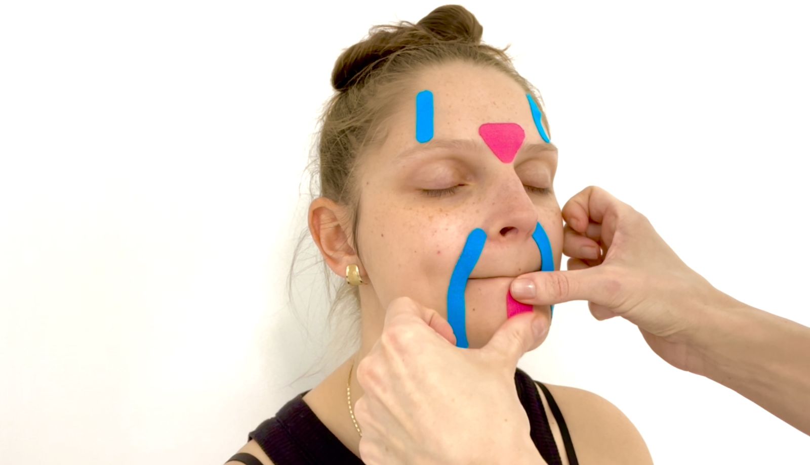 Face taping step by step – lifting tape application on the face during an online beauty school lesson.