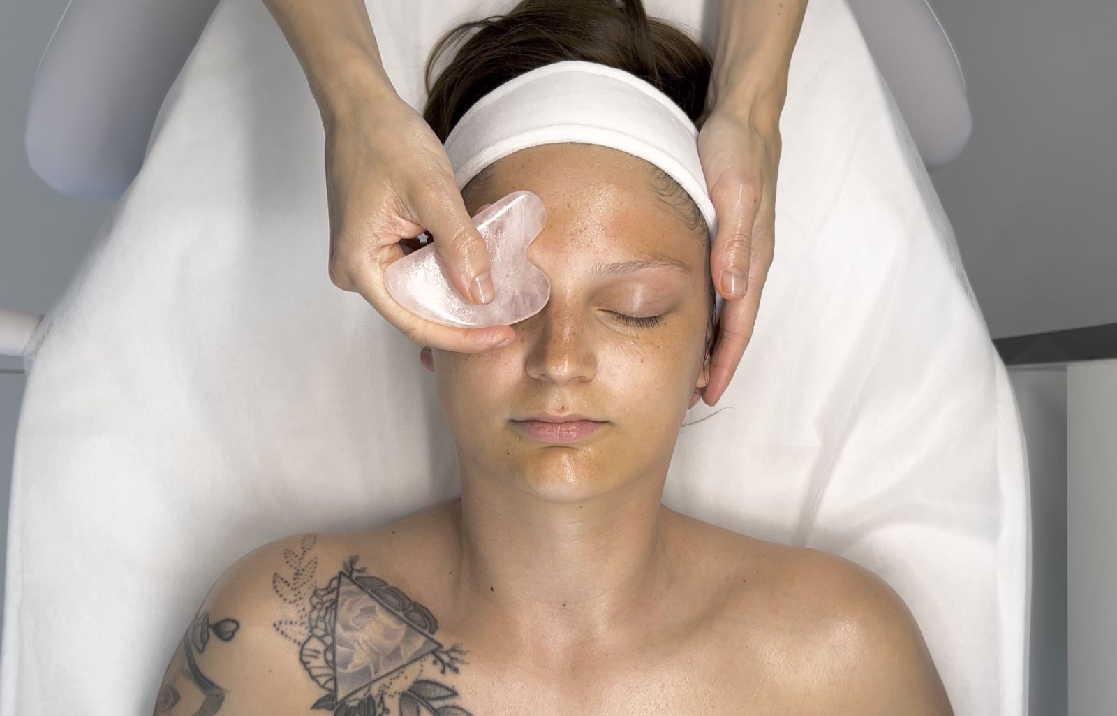 Facial Gua Sha massage – technique performed with a jade stone during an online beauty school lesson.